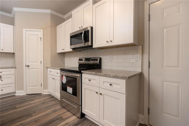 kitchen with appliances with stainless steel finishes, white cabinetry, ornamental molding, light stone countertops, and dark wood-type flooring