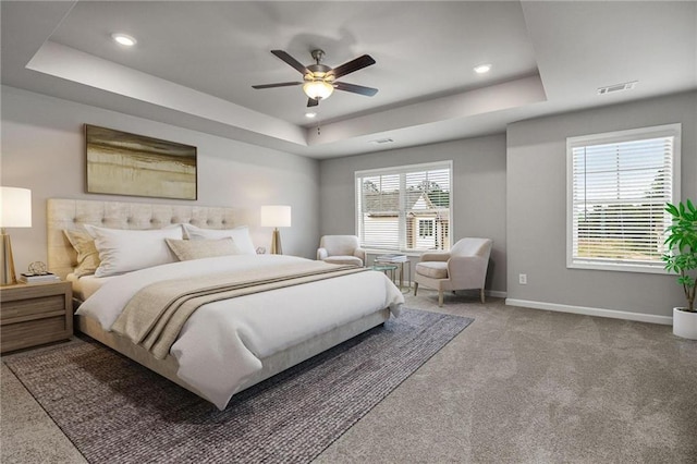 carpeted bedroom featuring ceiling fan and a tray ceiling