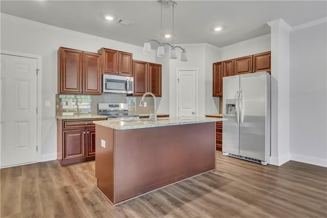 kitchen with sink, a center island with sink, appliances with stainless steel finishes, pendant lighting, and decorative backsplash