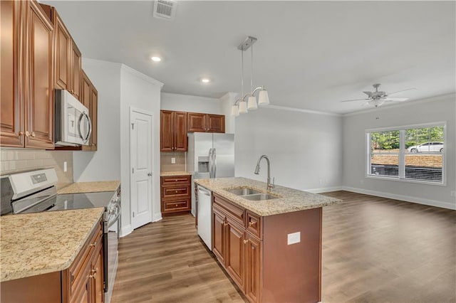 kitchen featuring sink, hanging light fixtures, ornamental molding, an island with sink, and stainless steel appliances