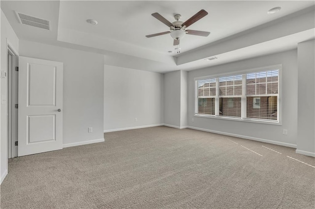 carpeted spare room featuring ceiling fan and a tray ceiling