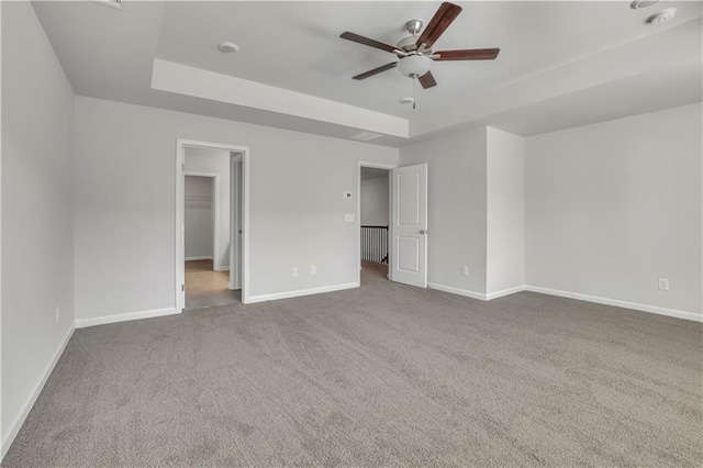 interior space with ceiling fan, carpet flooring, and a raised ceiling