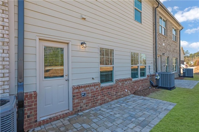 exterior space with central AC unit, a lawn, and a patio