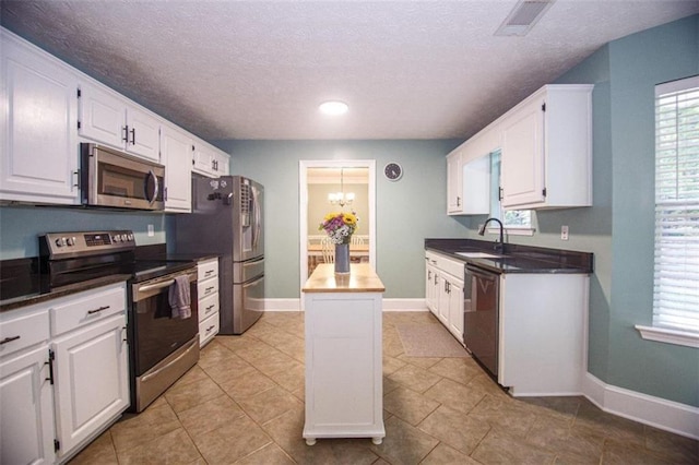 kitchen featuring sink, appliances with stainless steel finishes, an inviting chandelier, white cabinets, and a kitchen island