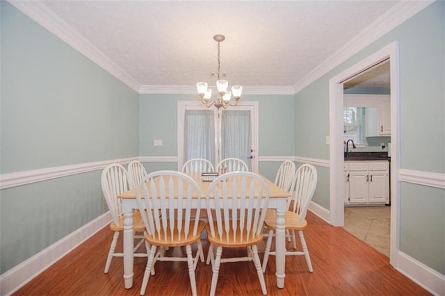 dining area featuring a notable chandelier, light hardwood / wood-style flooring, and ornamental molding