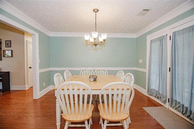 dining area with hardwood / wood-style flooring, crown molding, a chandelier, and a textured ceiling