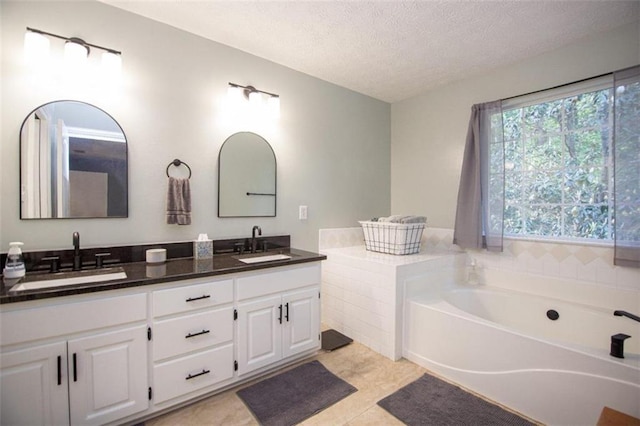 bathroom featuring vanity, a bath, tile patterned flooring, and a textured ceiling