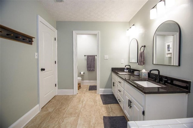 bathroom featuring vanity, toilet, and a textured ceiling