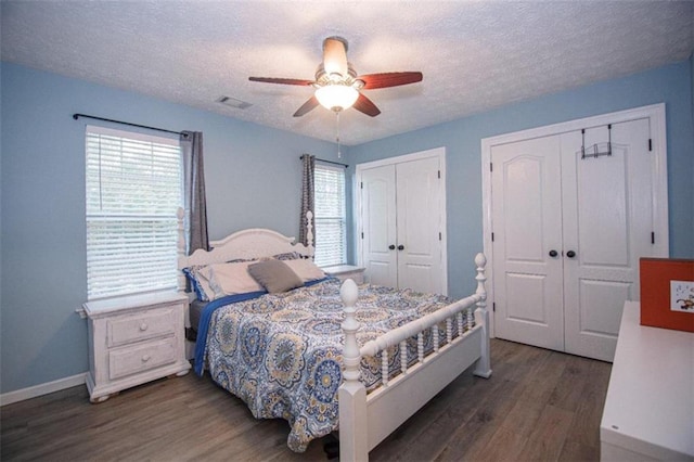 bedroom featuring multiple closets, ceiling fan, dark wood-type flooring, and a textured ceiling