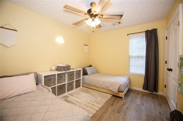 bedroom with ceiling fan, wood-type flooring, and a textured ceiling