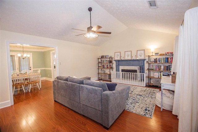 living room featuring lofted ceiling, hardwood / wood-style flooring, ceiling fan with notable chandelier, and a textured ceiling