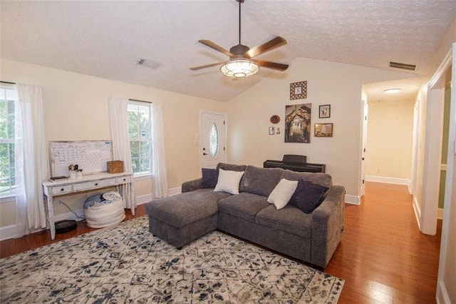 living room with lofted ceiling, ceiling fan, wood-type flooring, and a textured ceiling