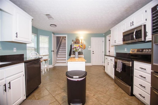 kitchen with white cabinetry, appliances with stainless steel finishes, wooden counters, and a textured ceiling