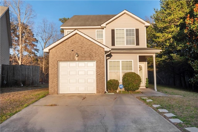 traditional-style home with a garage, concrete driveway, brick siding, and fence