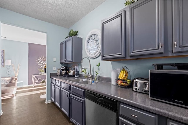 kitchen featuring a textured ceiling, a sink, stainless steel dishwasher, dark wood-style floors, and dark countertops