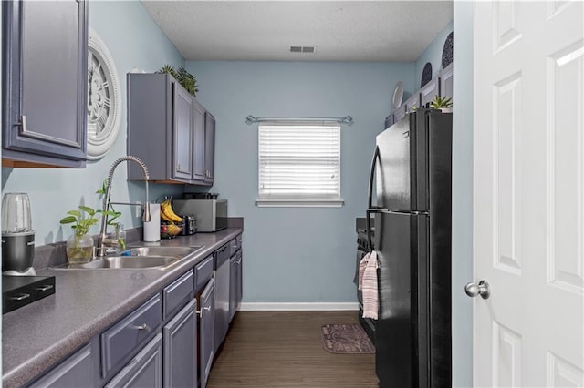 kitchen featuring visible vents, dark wood-type flooring, freestanding refrigerator, a textured ceiling, and a sink