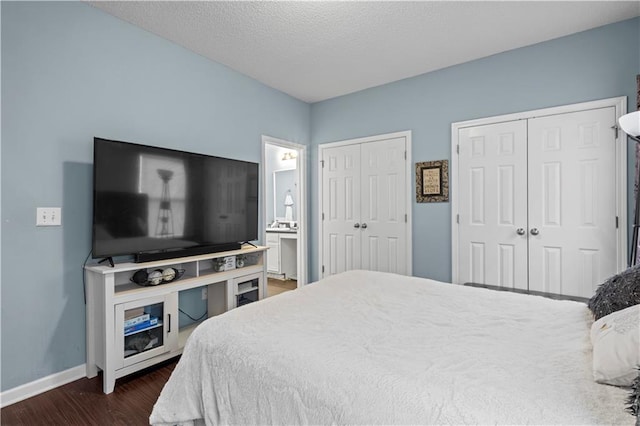 bedroom featuring multiple closets, a textured ceiling, baseboards, and dark wood-style floors