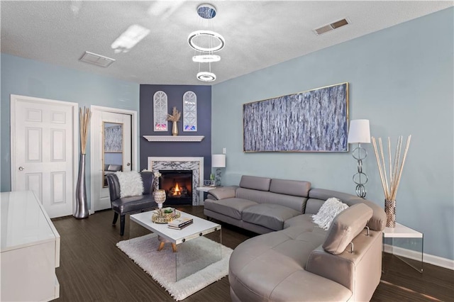 living area with a textured ceiling, visible vents, wood finished floors, and a tiled fireplace