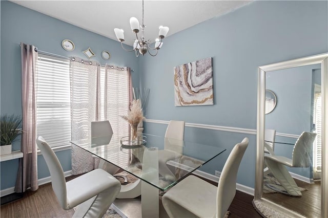 dining space featuring baseboards, plenty of natural light, wood finished floors, and a notable chandelier