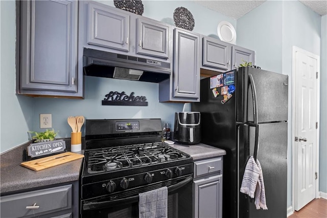 kitchen featuring a textured ceiling, black appliances, gray cabinets, and under cabinet range hood