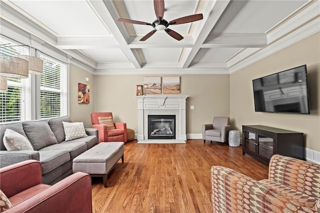 living area featuring ceiling fan, a glass covered fireplace, light wood finished floors, coffered ceiling, and beamed ceiling
