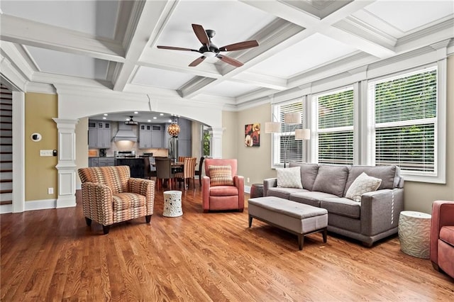living area with ornate columns, arched walkways, a ceiling fan, wood finished floors, and coffered ceiling