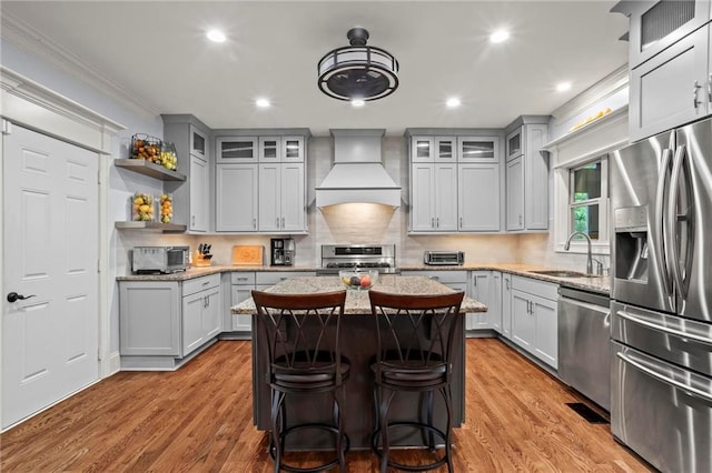 kitchen with stainless steel appliances, custom range hood, a sink, a kitchen island, and gray cabinets