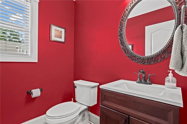half bath featuring baseboards, toilet, and vanity