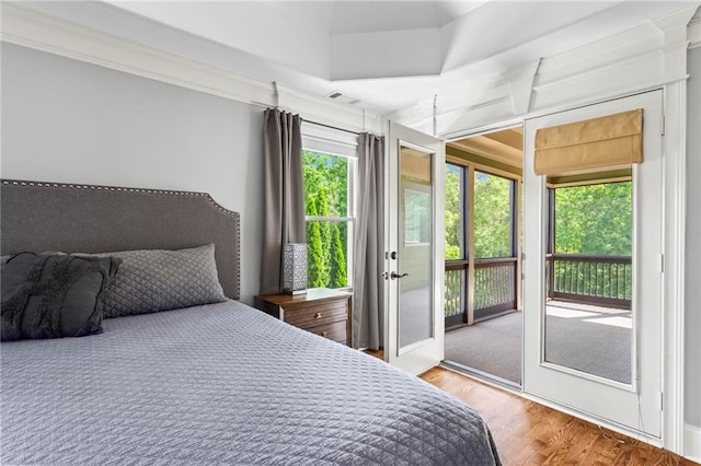 bedroom with access to outside and wood finished floors
