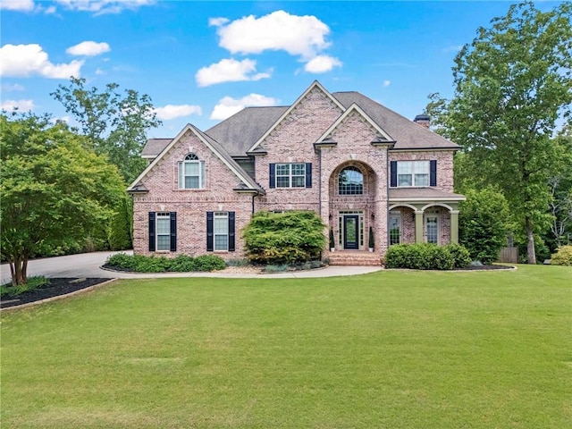 traditional-style house featuring brick siding, a front lawn, and a chimney