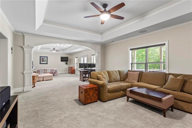 living area with ornate columns, ceiling fan, a raised ceiling, arched walkways, and crown molding