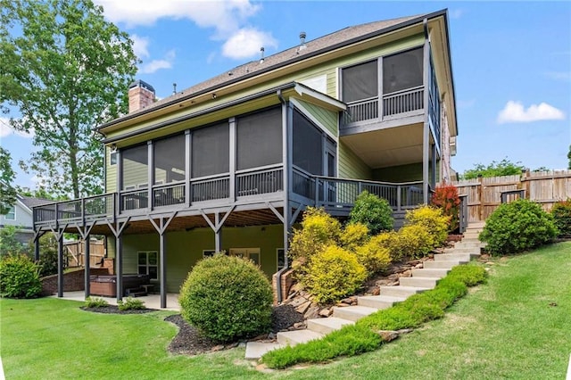 back of property with a hot tub, a sunroom, stairs, a chimney, and a patio area