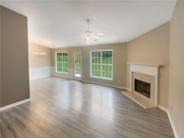 unfurnished living room with a high end fireplace, dark hardwood / wood-style flooring, and ceiling fan with notable chandelier