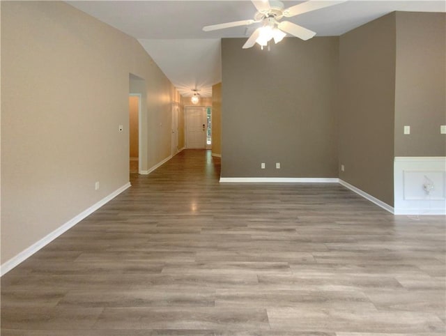 empty room with vaulted ceiling, ceiling fan, and light hardwood / wood-style floors