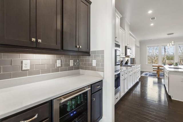 kitchen featuring decorative backsplash, dark brown cabinetry, white cabinets, and beverage cooler