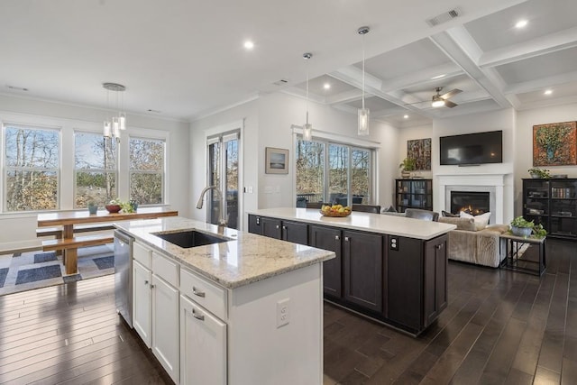 kitchen with sink, light stone countertops, an island with sink, decorative light fixtures, and white cabinetry