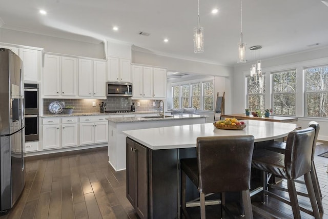 kitchen with sink, white cabinetry, stainless steel appliances, and an island with sink