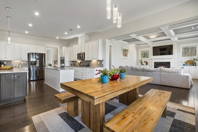 dining room with beam ceiling, sink, coffered ceiling, dark hardwood / wood-style flooring, and crown molding