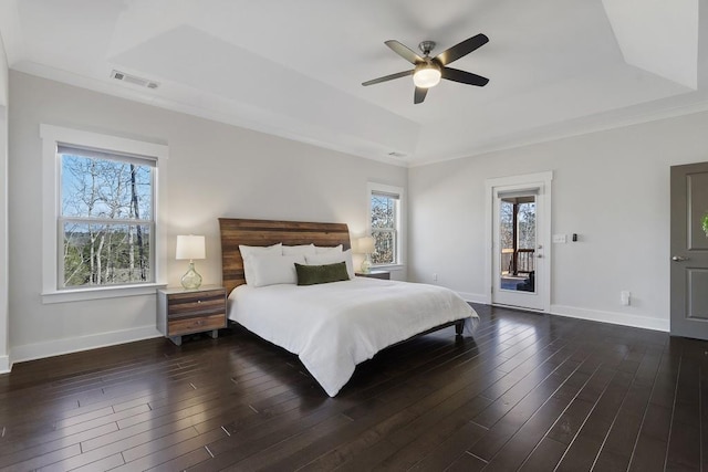 bedroom with a raised ceiling, ceiling fan, dark hardwood / wood-style floors, access to exterior, and multiple windows