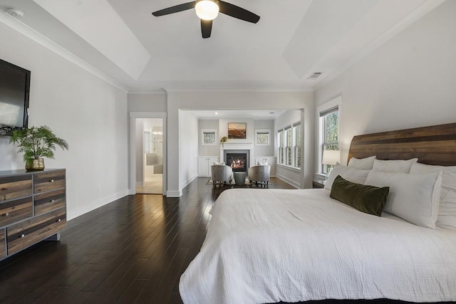 bedroom with a tray ceiling, ceiling fan, ornamental molding, and dark hardwood / wood-style floors