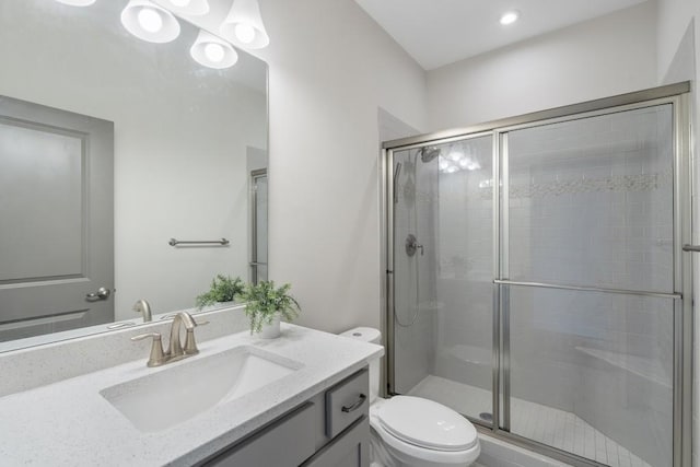 bathroom featuring a shower with door, vanity, and toilet