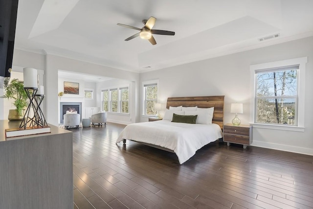 bedroom with a raised ceiling, ceiling fan, and dark hardwood / wood-style flooring