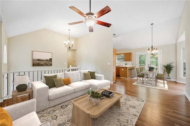 living room with hardwood / wood-style floors, ceiling fan with notable chandelier, and vaulted ceiling