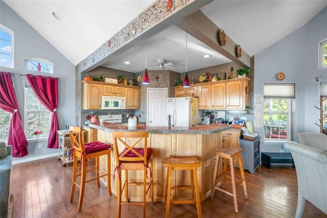 kitchen featuring white appliances, a kitchen bar, dark hardwood / wood-style flooring, and light brown cabinets