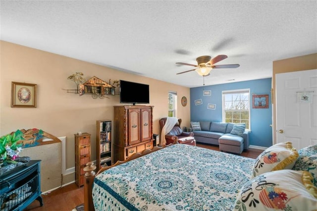 bedroom with ceiling fan, dark hardwood / wood-style flooring, and a textured ceiling