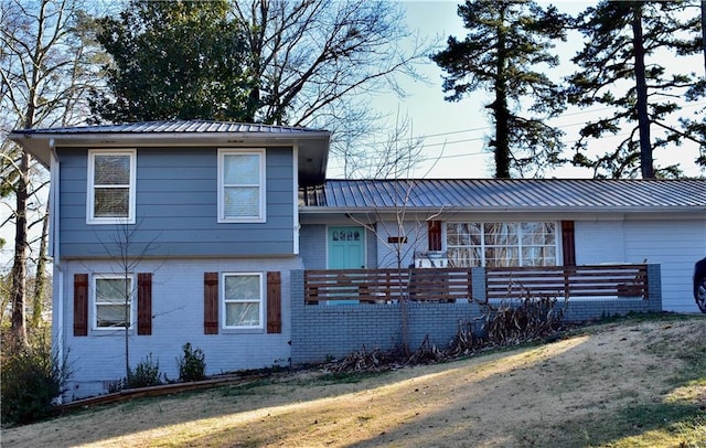 tri-level home with metal roof, brick siding, and a front yard