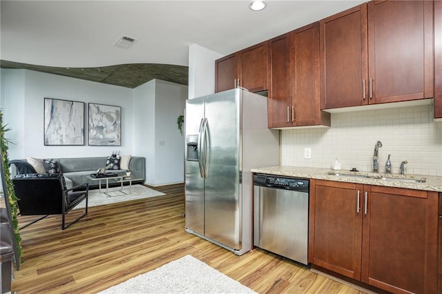 kitchen with light stone countertops, appliances with stainless steel finishes, sink, and light hardwood / wood-style floors