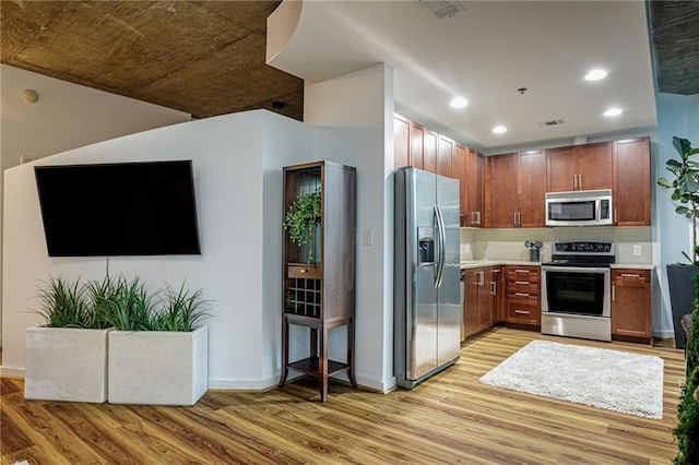 kitchen with decorative backsplash, stainless steel appliances, and light hardwood / wood-style flooring