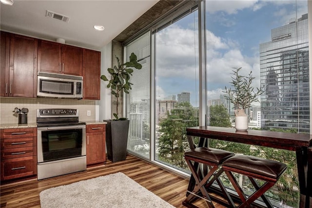 kitchen featuring backsplash, stainless steel appliances, light stone countertops, and light wood-type flooring