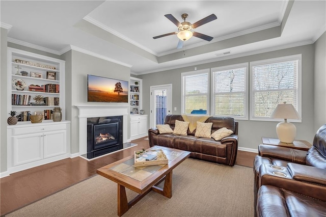 2735 Kimblewick Ct, Cumming, GA 30040 - living area featuring built in shelves, wood finished floors, a high end fireplace, a tray ceiling, and crown molding